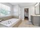 Bright main bathroom featuring a soaking tub, a vanity with storage, and access to a walk-in closet at 1930 Southridge Dr, Belmont, NC 28012