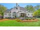 Beautiful rear exterior with a manicured lawn, white brick facade, outdoor seating, and lush greenery at 1976 Ferncliff Rd, Charlotte, NC 28211
