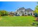 Expansive backyard featuring a well-maintained lawn, white brick house, patio area, and mature trees at 1976 Ferncliff Rd, Charlotte, NC 28211