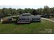 Aerial view of the home, set on a green lot with mature trees, a fence, outbuildings and a long driveway at 2055 Cauble Rd, Salisbury, NC 28144