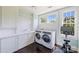 Bright laundry room with modern washer/dryer, white tile, and ample counter space at 2101 Dilworth W Rd, Charlotte, NC 28203