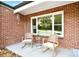 Inviting front porch area featuring two rocking chairs, brick walls, and a view of the landscaped yard at 2121 Arnold Dr, Charlotte, NC 28205
