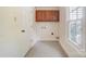 Functional laundry area featuring tile floor, wooden cabinets, and window for natural light at 2221 Hamilton Mill Rd, Charlotte, NC 28270
