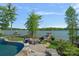 Picturesque backyard with a swimming pool, a fire pit, lush landscaping, and breathtaking lake views at 4109 Arbor Spring Ct, Belmont, NC 28012