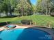 Expansive backyard with a pool, manicured lawn, and picturesque lake views at 5517 Mountain Point Ln, Charlotte, NC 28216