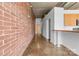 Hallway with exposed brick wall, concrete floor leading to a laundry area, and open concept kitchen at 626 N Graham St # 405, Charlotte, NC 28202