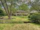 A spacious backyard with mature trees surrounds a brick home with a walkout patio perfect for entertaining at 6420 Saint John Ln, Charlotte, NC 28210