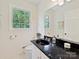 Bright bathroom featuring dark marble countertops, toilet and a bright window with natural light at 6420 Saint John Ln, Charlotte, NC 28210