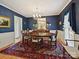 Elegant dining room featuring dark blue walls, classic furniture, and a decorative rug at 6420 Saint John Ln, Charlotte, NC 28210