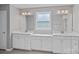 Bathroom boasts dual vanities with modern fixtures, white cabinetry, and a window offering natural light at 708 Brookmeade Dr, Waxhaw, NC 28173