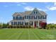 Beautiful two-story home with a manicured lawn, lush landscaping, and a welcoming red front door at 708 Brookmeade Dr, Waxhaw, NC 28173