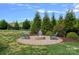 A stone firepit surrounded by chairs, landscaping and green grass at 708 Brookmeade Dr, Waxhaw, NC 28173