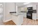 Open kitchen with white cabinetry, island with granite countertops, and stainless steel appliances at 721 Broad St, Kannapolis, NC 28081
