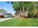 A two-story home with red shutters, a long driveway, and a detached garage in a leafy setting at 7220 Spring Morning Ln, Charlotte, NC 28227
