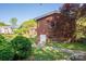 Back exterior view of brick home featuring lush greenery, patio, and access to backyard at 821 Mark St, Belmont, NC 28012