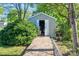 Outdoor shed with open doors and concrete access provides ample storage in a serene, green setting at 821 Mark St, Belmont, NC 28012