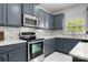 Well-lit kitchen features stainless steel appliances, blue cabinets, granite countertops, and a stylish backsplash at 8453 Mossy Cup Trl, Harrisburg, NC 28075