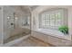 Luxurious bathroom features a soaking tub, a glass-enclosed shower and stone tile flooring at 914 Elizabeth Ln, Matthews, NC 28105