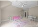 Open bedroom area featuring a pink sofa, white desk, and patterned rug with soft lighting and a ceiling fan at 914 Elizabeth Ln, Matthews, NC 28105