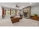 Cozy living room with a stone fireplace, leather sofa, and large windows offering views of the backyard at 914 Elizabeth Ln, Matthews, NC 28105
