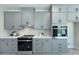 Kitchen area with stainless steel oven, gray cabinets, white countertops, and tile backsplash at 1033 Harrogate Dr, Bessemer City, NC 28016