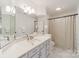 Well-lit bathroom with light blue cabinets, quartz countertop, tile flooring, and a decorative shower curtain at 108 Tall Oak Dr, Mooresville, NC 28117