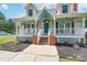 Inviting front porch with brick steps, hanging plants, rocking chairs, and a teal front door at 1228 Quiet Acres Rd, Rock Hill, SC 29732