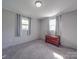 A well-lit bedroom with grey carpet and paneled walls, with two windows, soft blue curtains, and a vintage wooden chest at 1315 Holshouser Rd, Rockwell, NC 28138