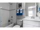Well-lit bathroom featuring a white sink vanity and toilet, complemented by white tiled shower and blue accent towels at 13304 Chopin Ridge Dr, Huntersville, NC 28078