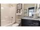 Bathroom with dark vanity, granite countertop, framed art, and white bath and shower with tiled walls at 13304 Chopin Ridge Dr, Huntersville, NC 28078