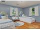 This bright bedroom features two twin beds with light blue bedding and a matching lamp on a white nightstand at 1331 Mccorkle Rd, Charlotte, NC 28214