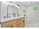 Bright bathroom with a double sink, wood cabinets, granite countertops, and octagon window at 143 Ross Rd, Mooresville, NC 28117