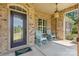 Welcoming front porch featuring rocking chairs, a decorative door, and brick accents at 15210 Pavilion Valley Cir, Huntersville, NC 28078