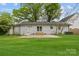 This backyard features a well maintained grass area, an attached patio, and a home with white painted brick at 1601 Gambia St, Charlotte, NC 28208