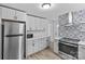 Modern kitchen features white cabinets, stainless steel appliances, and eye-catching patterned backsplash at 1601 Gambia St, Charlotte, NC 28208