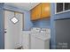 A laundry room showing a washer, a dryer, and overhead cabinets at 189 Woodwinds Dr, Mooresville, NC 28115