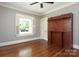 A bright bedroom featuring hardwood floors, a window with white shutters, and a built-in wooden shelving unit at 2015 Dilworth E Rd, Charlotte, NC 28203