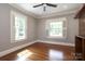 A bright bedroom with hardwood floors, two windows with white shutters, gray walls, and a ceiling fan at 2015 Dilworth E Rd, Charlotte, NC 28203