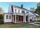 Side view of a white two-story house with a brick facade, porch with columns, and classic black shutters at 2015 Dilworth E Rd, Charlotte, NC 28203