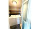 Functional laundry area with a washer, dryer, and wood shelving for storage at 207 Morris St, Kings Mountain, NC 28086