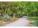 Long gravel driveway leading to home amid lush greenery and towering trees, offering a secluded and welcoming entrance at 2415 Hargette Rd, Monroe, NC 28112