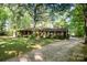 A front view of the stone and wood paneled home surrounded by mature trees at 2415 Hargette Rd, Monroe, NC 28112