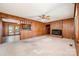 Cozy living room featuring wood paneling, a brick fireplace, and a ceiling fan, creating a warm and inviting atmosphere at 2415 Hargette Rd, Monroe, NC 28112