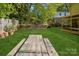 Spacious backyard featuring green grass, a wooden picnic table, and mature trees, perfect for outdoor activities and relaxation at 308 Greenwood Pl, Belmont, NC 28012