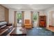 Bright living room featuring a leather sofa, large windows with backyard views, and a vintage cabinet at 308 Greenwood Pl, Belmont, NC 28012