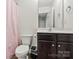A simple bathroom features a toilet, dark sink vanity, and shower behind a pink curtain at 3623 Danvers St, Charlotte, NC 28213