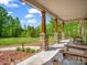 Inviting front porch with stone columns, wooden furniture and a view of the green yard at 575 Hill Rd, Lincolnton, NC 28092