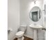 Bright half bathroom with a pedestal sink, round mirror and wood-look flooring at 609 Kahana River Rd, Fort Mill, SC 29715