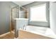 Bright bathroom featuring a luxurious soaking tub, a glass-enclosed shower, and tiled floors and accents at 609 Kahana River Rd, Fort Mill, SC 29715