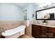 Light-filled bathroom features a soaking tub, marble accent wall, granite countertop, and decorative flower arrangement at 8013 Sheckler Ln, Matthews, NC 28104